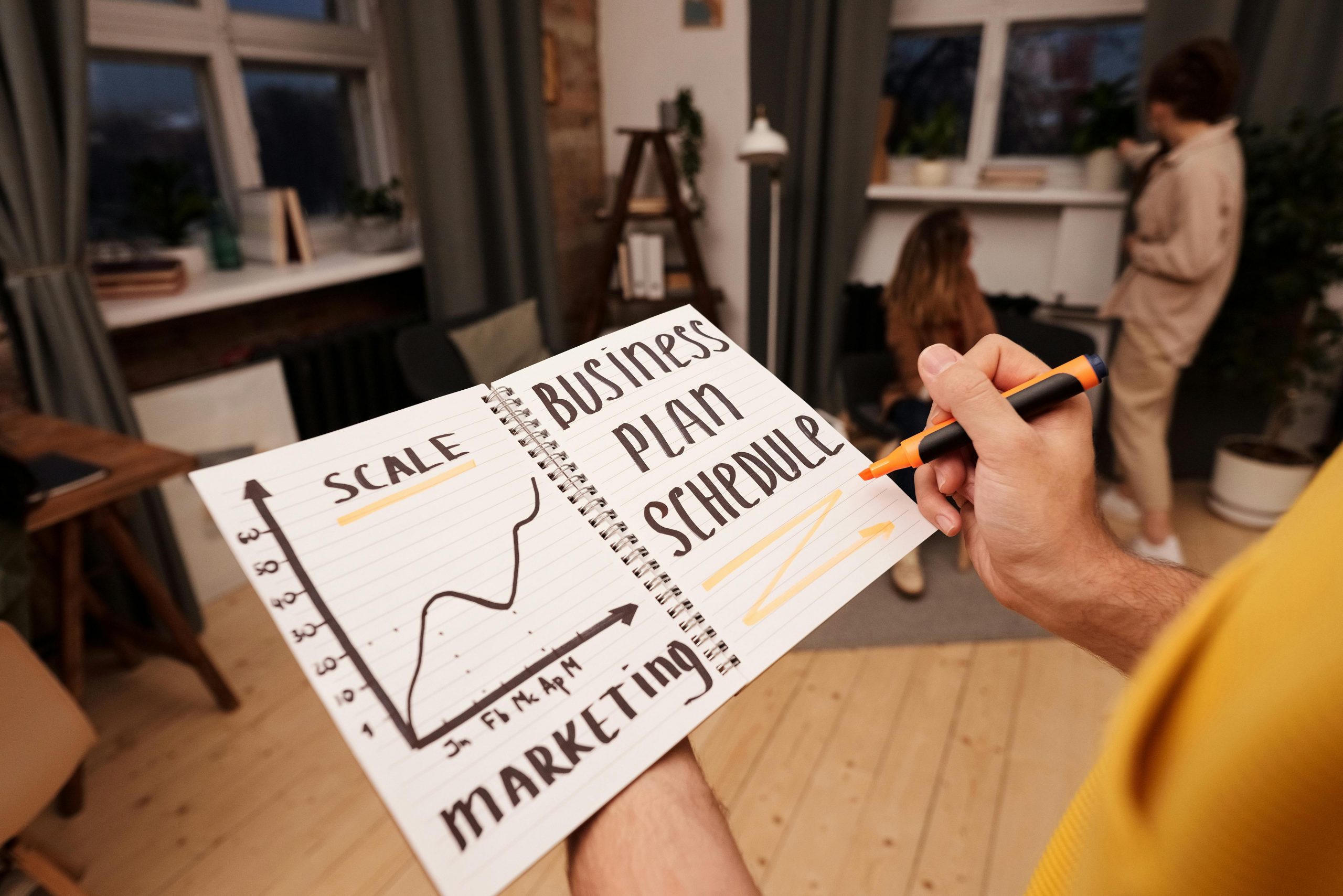 Person holding a notebook with planning details and graph for business strategy indoors.